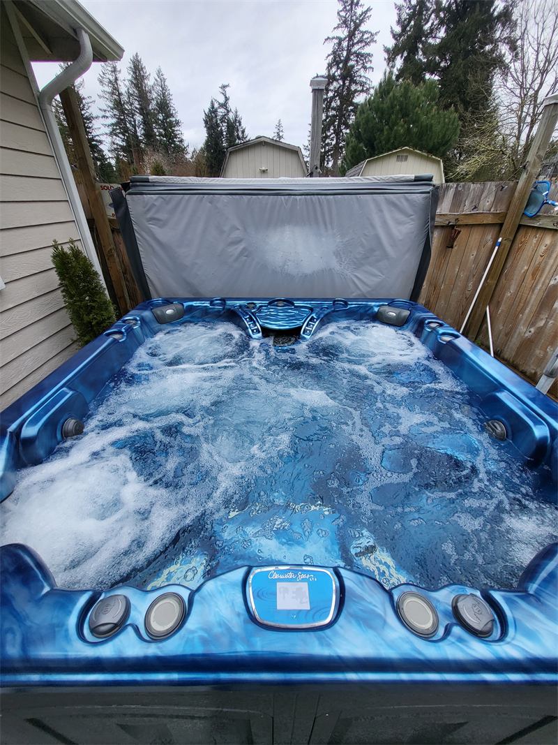 Hot tub with jets running and clear bubbling water on a backyard deck