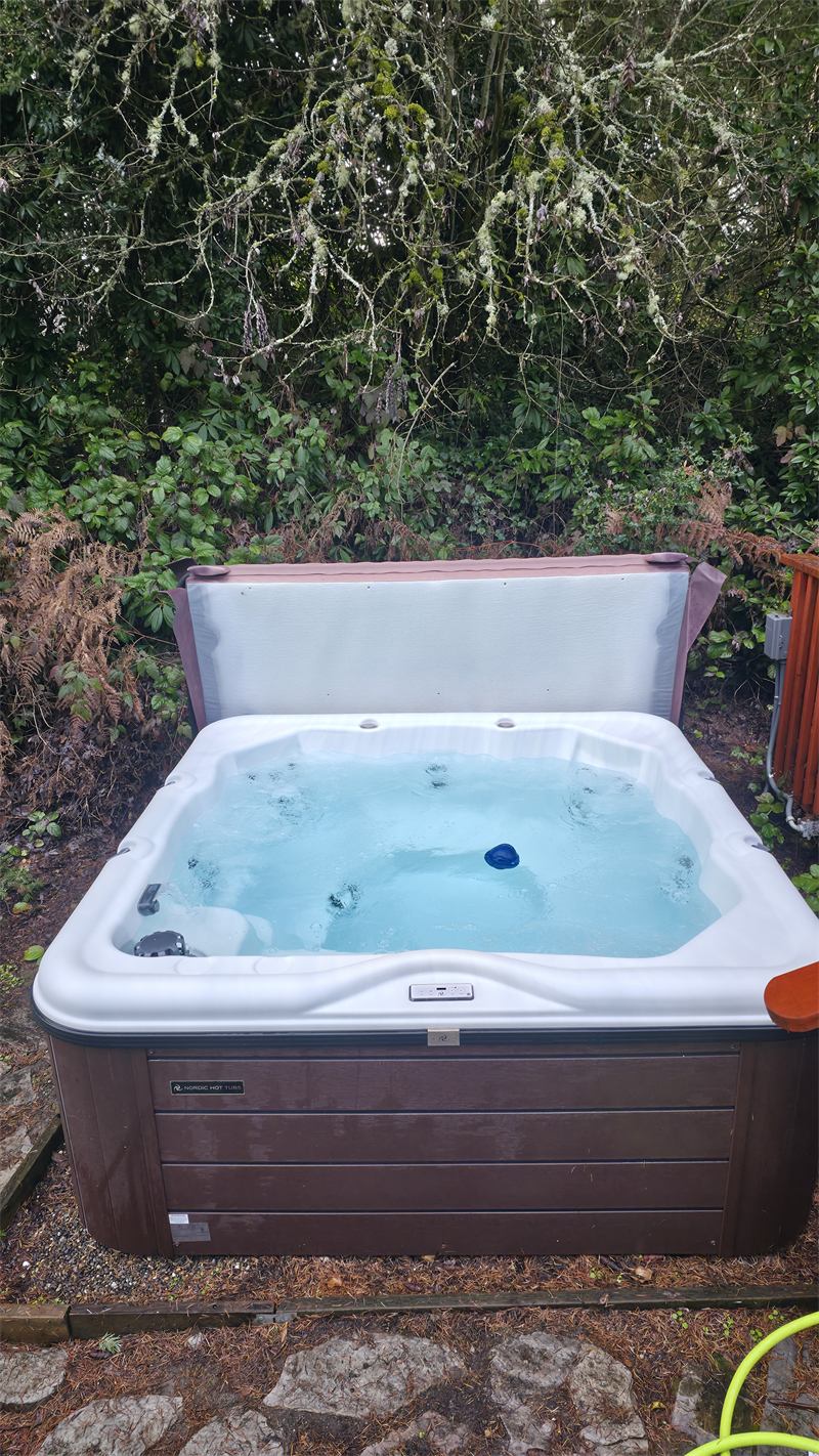 Square hot tub with bubbling aqua water in a garden