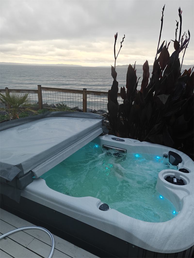 Hot tub glowing teal at dusk beside the water