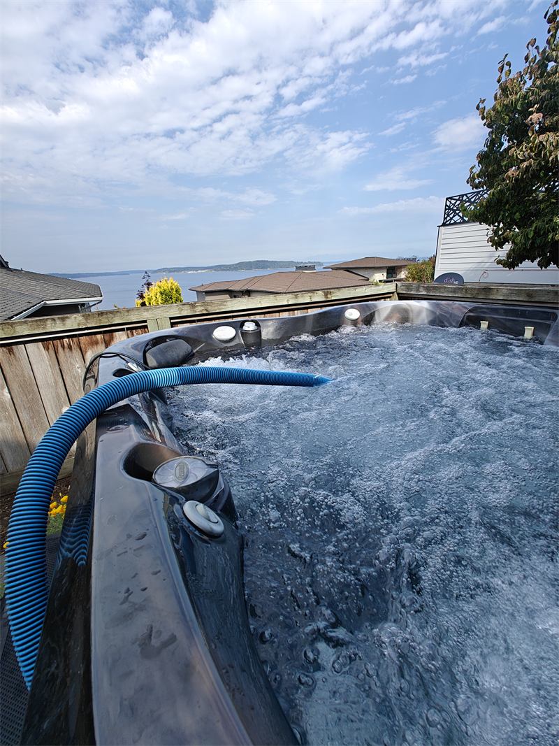 Hot tub churning with clean water and a waterfront view behind