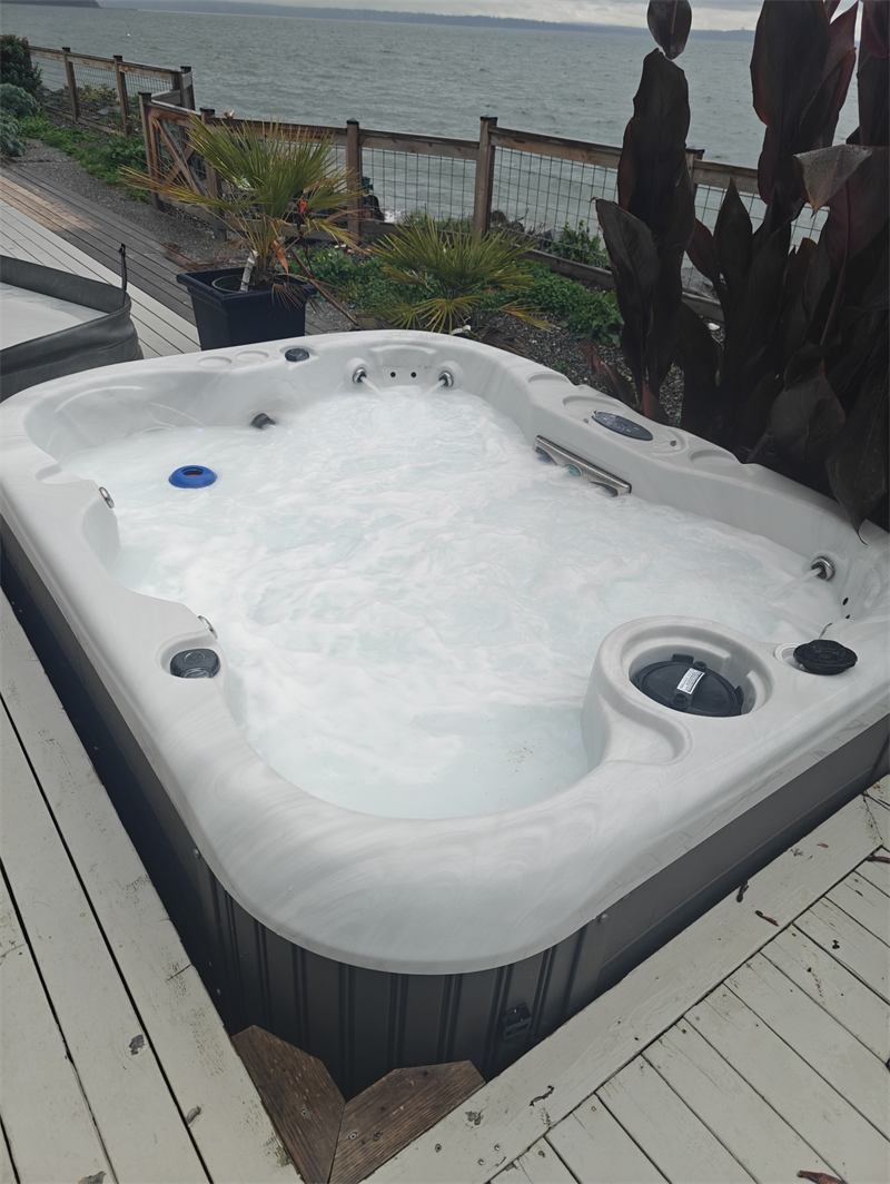 Hot tub with clear blue water on a deck overlooking open water