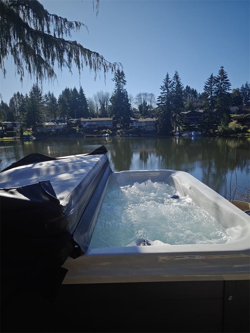 Hot tub with churning clear water beside a calm lake at sunset