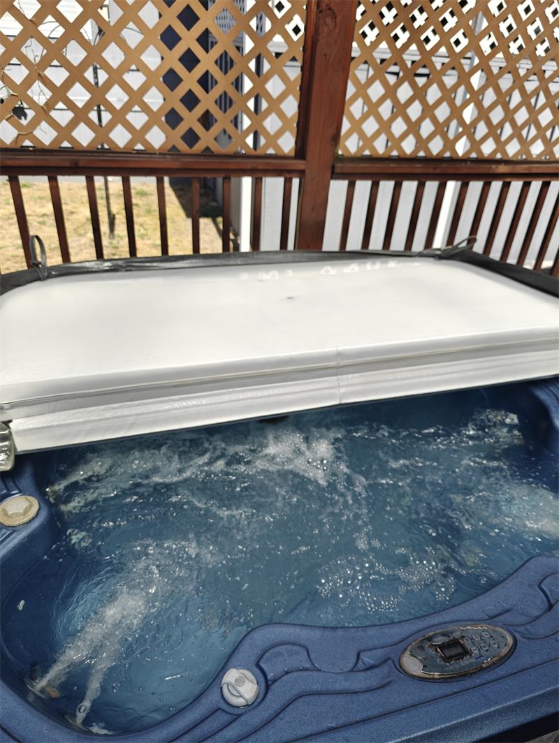 Blue hot tub with clean churning water and its cover lifted