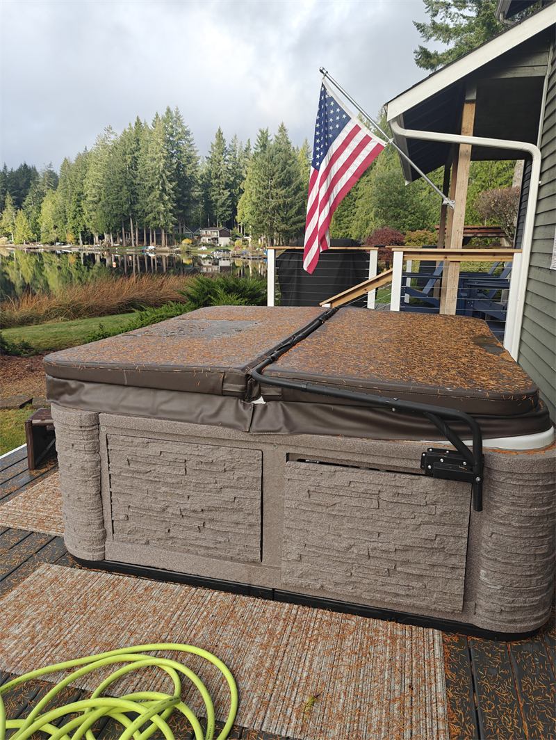 Hot tub cover buried in pine needles before service at a lakefront home
